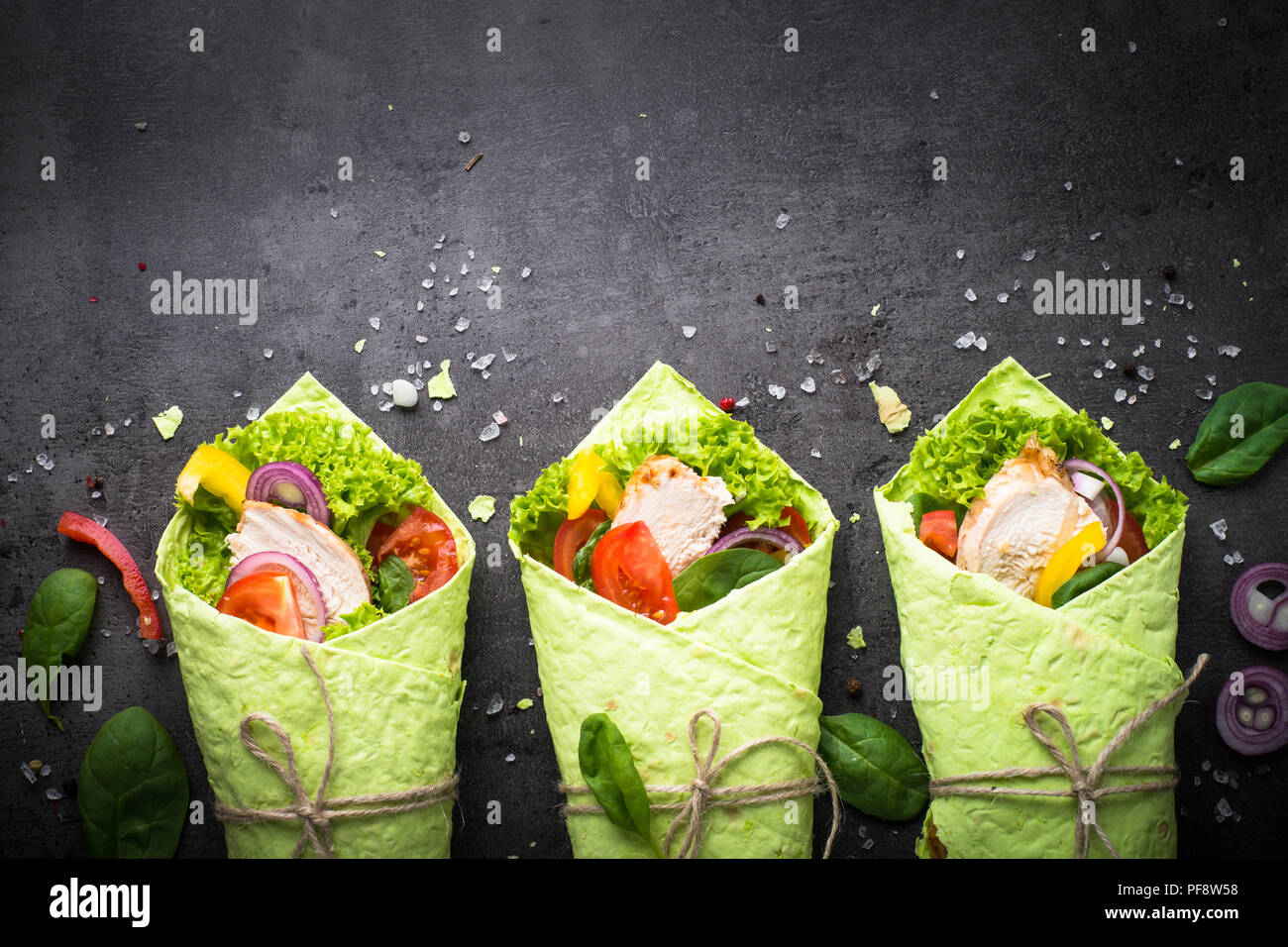 Grüne Spinat Tortilla mit Hähnchen und Gemüse. Draufsicht auf schwarzem Schiefer Tisch mit kopieren. Gesunden Snack. Stockfoto