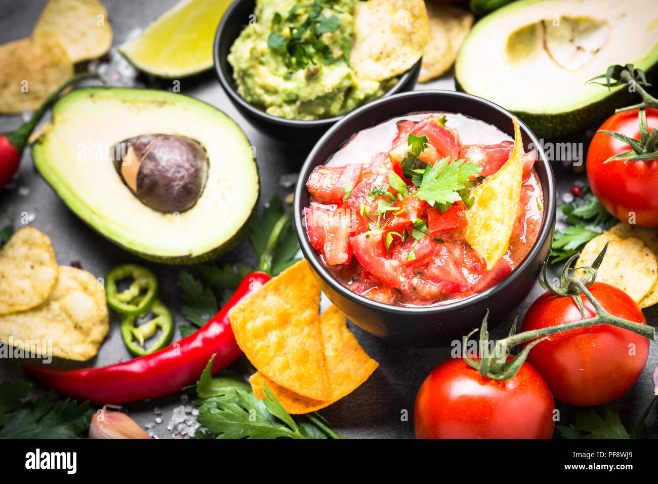 Lateinamerikanische mexikanisches Essen party Soße Guacamole, Salsa, Chips und Zutaten auf Schwarz. Stockfoto