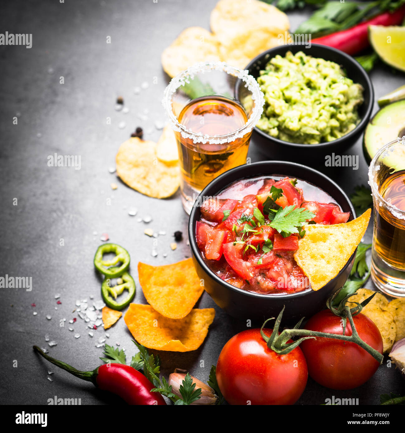 Lateinamerikanische mexikanisches Essen party Soße Guacamole, Salsa, Chips und Tequila auf Schwarz. Stockfoto