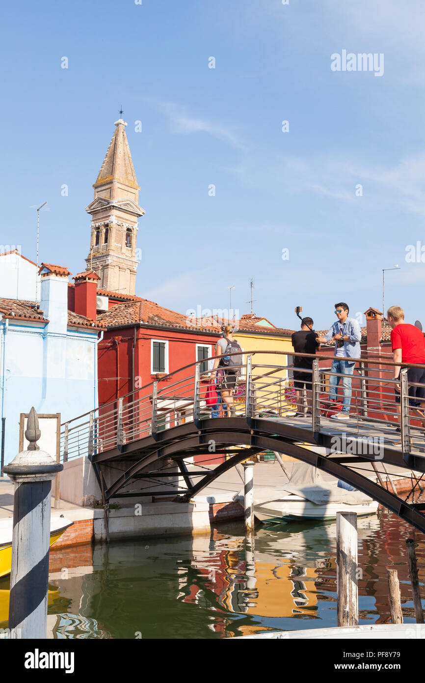 Sonnenuntergang in der farbenfrohen Fischerdorf auf der Insel Burano, Venedig, Venetien, Italien, Touristen auf Brücke selfies, Reflexionen Canal, lehnte sich Bell auf. Stockfoto