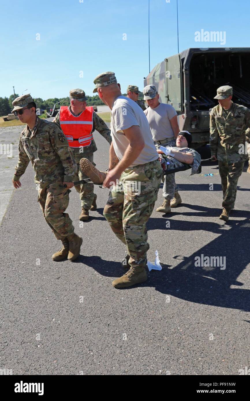 Teilnehmenden Soldaten in einem Mass Casualty übung Bewegen ein verletzter Soldat von einem militärischen Krankenwagen in der Nähe von Ziemsko Flugplatz, Polen, 5. Juni 2018. Die Masse Unfall- Übung war Teil der Validierungsphase für das 1171St Bereich Medical Support Unternehmen, Michigan National Guard, der in der Region einmal später im nächsten Jahr bereitzustellen. (Michigan National Guard Stockfoto