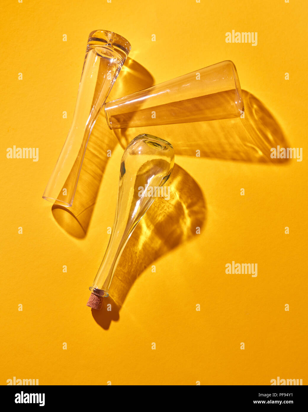 Leere Glasflaschen liegen auf einem gelben Hintergrund mit Schatten und Reflexionen. Ansicht von oben. Stockfoto