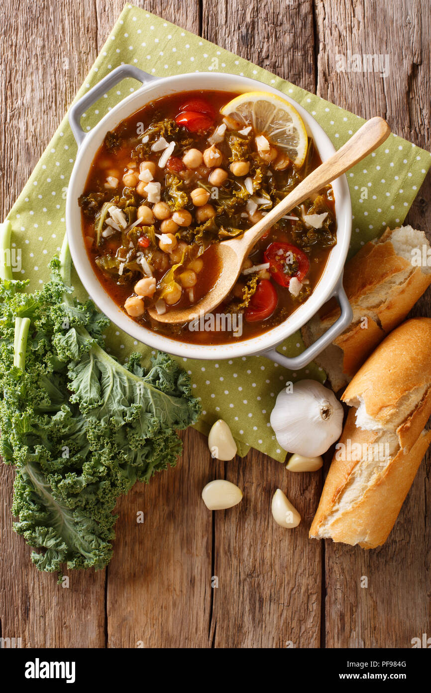 Suppe mit Kichererbsen, Grünkohl, Tomaten, Knoblauch und Kartoffeln mit Zitrone schließen in einer Schüssel auf dem Tisch. Vertikal oben Ansicht von oben Stockfoto