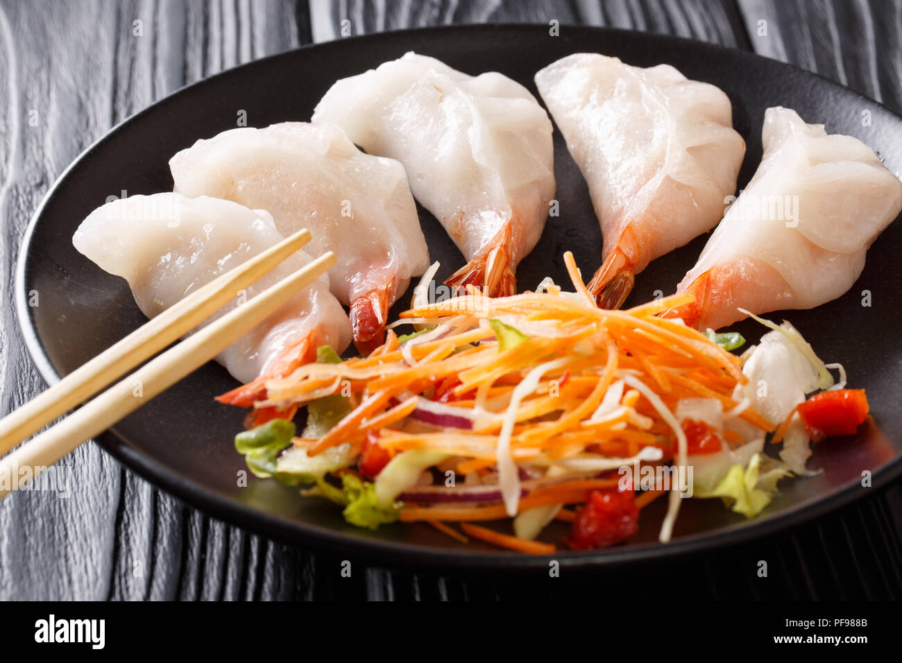 Chinesische Knödel jiaozi mit Garnelen mit Salat in der Nähe serviert auf einem Teller. Horizontale Stockfoto