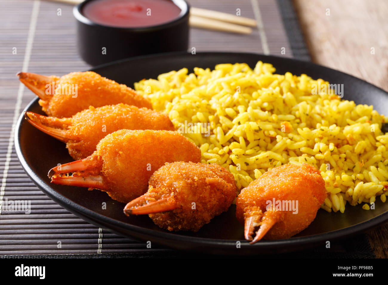 Fried Crab Claws in Paniermehl mit würzigen gelber Reis close-up auf einem Teller auf dem Tisch. Horizontale Stockfoto