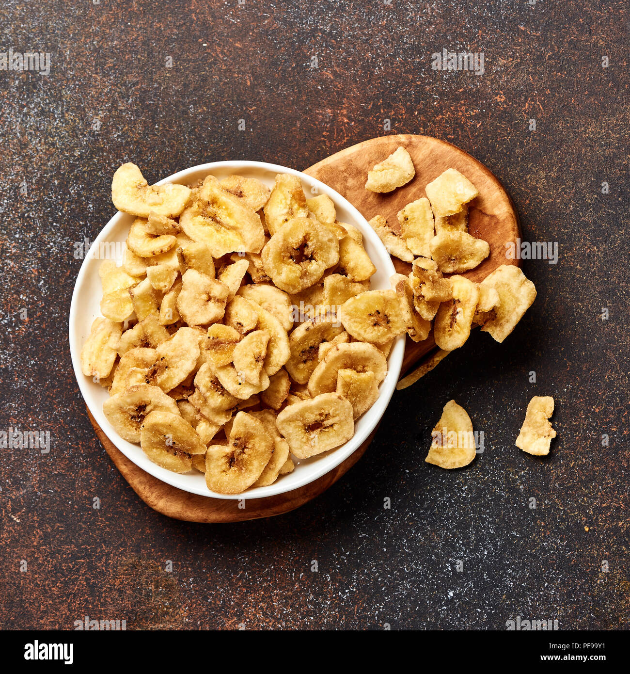 Getrocknete Bananenscheiben auf braunem Hintergrund. Blick von oben auf die Banane crunchies. Stockfoto