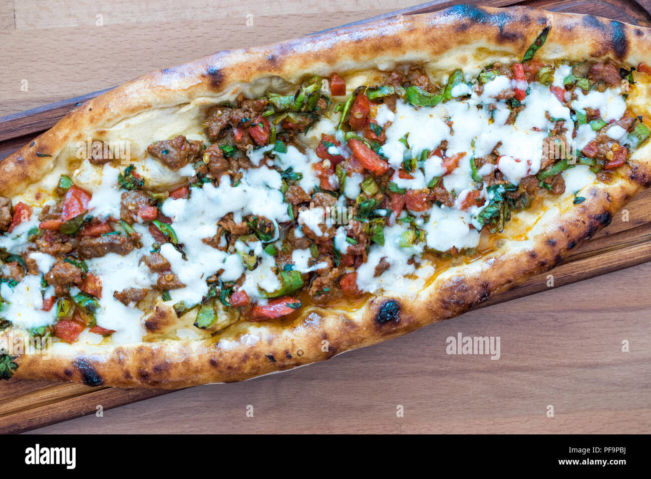 Türkische gemischt Pide mit Hackfleisch, Käse, Wurst (sucuk), Tomaten und Paprika, serviert mit Salat und Gurken. Traditionelle Speisen. Stockfoto