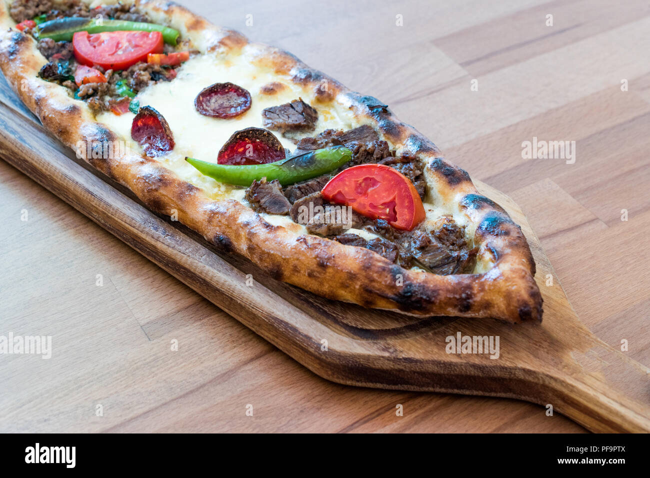 Türkische gemischt Pide mit Hackfleisch, Käse, Wurst (sucuk), Tomaten und Paprika, serviert mit Salat und Gurken. Traditionelle Speisen. Stockfoto