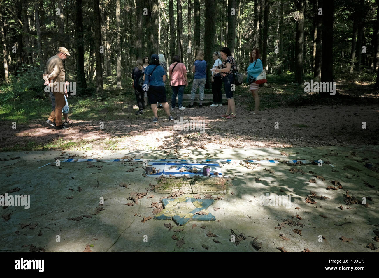 Die Teilnehmer der Reiseagentur ROOTKA, die sich auf jüdische Kulturreisen in Osteuropa spezialisiert hat, stehen neben einer riesigen Betonplatte, die Massengrab der von Deutschen während des Zweiten Weltkriegs getöteten Juden im Wald von Bronytsya markiert, Ein kleines Dorf nördlich der Stadt Drohobych im Gebiet Lwiw, Ukraine. Stockfoto