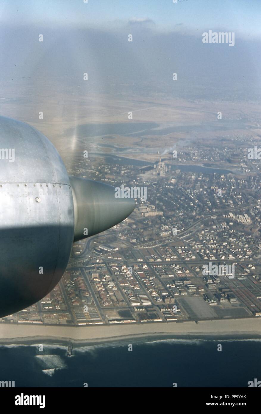 Luftbild mit Blick nach Norden der Nachbarschaften von Edgemere, Wavecrest, Bayswater, der auf der südlichen Halbinsel Rockaway in Queens, New York City, Juni, 1959. Der propeller Motor einer Swissair DC7 C Flugzeug ist im linken Vordergrund sichtbar, Kreuzfahrt über den Atlantik. () Stockfoto
