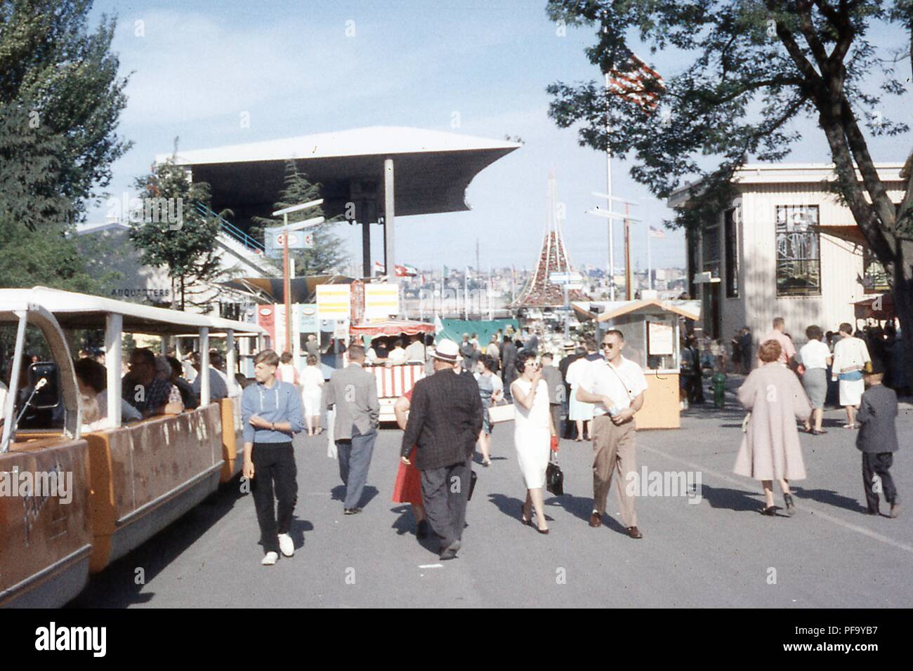 Szene der Besucher zu Fuß durch die Jahrhundert 21 Exposition Seattle's World Fair, in Seattle, Washington, Juli, 1962. Am linken Rand ist ein Fairliner People Mover Kreuzfahrt Vergangenheit Memorial Stadium im Hintergrund. () Stockfoto