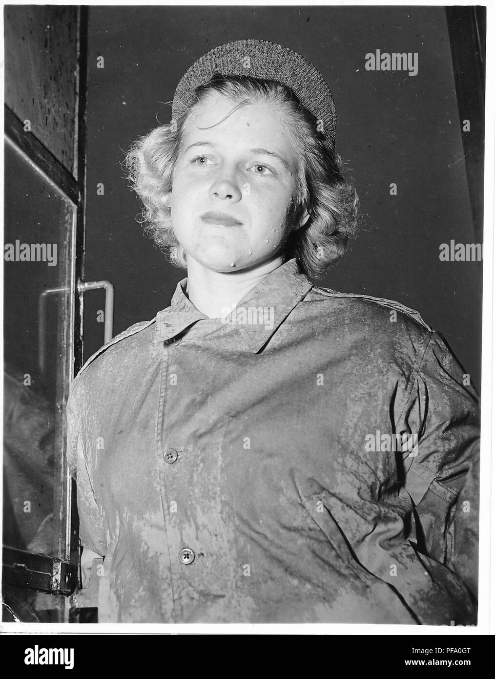 Schwarz-weiß Foto zeigt eine junge blonde Frau, von der Taille bis, das Tragen eines verregneten militärischen Jacke und eine Mütze mit Krempe, mit Regentropfen auf die Wange und einen ernsten Gesichtsausdruck, wahrscheinlich fotografierte während des Zweiten Weltkrieges, 1945. () Stockfoto