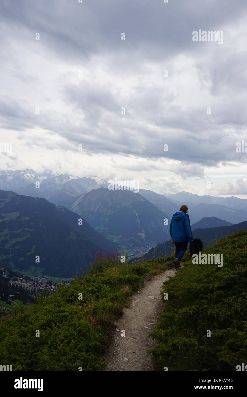 Mann und ein Berner Sennenhund, wachen auf dem Weg in den Schweizer Alpen Stockfoto