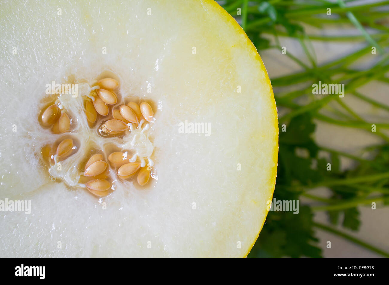 Die Hälfte der Galia-melone über petersilie Hintergrund. Nahaufnahme Stockfoto
