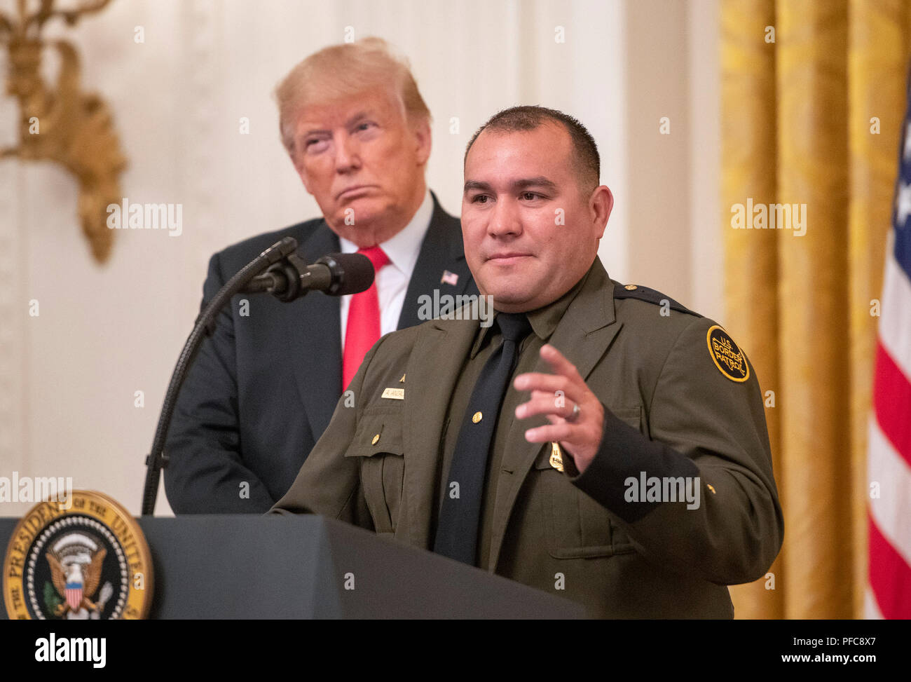 Washington, Vereinigte Staaten von Amerika. 20 Aug, 2018. Border Patrol-Agenten Adrian Anzaldua macht spontane Bemerkungen wie United States President Donald J. Trumpf auf während einer der Alute, um die Helden der Einwanderungs- und Zollbehörden und Zoll- und Grenzschutz' durch den Präsidenten im East Room des Weißen Hauses in Washington, DC am Montag, August 20, 2018 gehostete aussieht. In seinen Ausführungen, die Präsident lobte Anzaldua, ein Hispanic-American Border Patrol-Agent, als jemand, der die "perfekt Englisch spricht." Quelle: Ron Sachs/CNP | Verwendung der weltweiten Kredit: dpa/Alamy leben Nachrichten Stockfoto