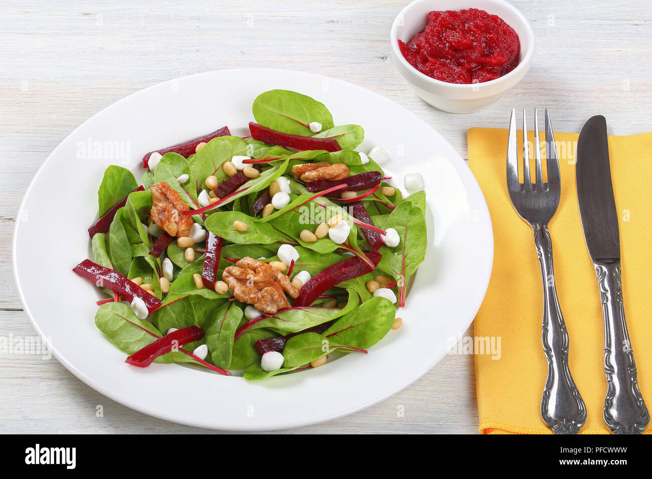 Mangold, granulierte Hüttenkäse, Rote-beete-Stücke und karamellisierten Nüsse frische Salat auf weiße Platte, auf alten Tisch. cranberry Sauce in der Schüssel, Ansicht von ab Stockfoto