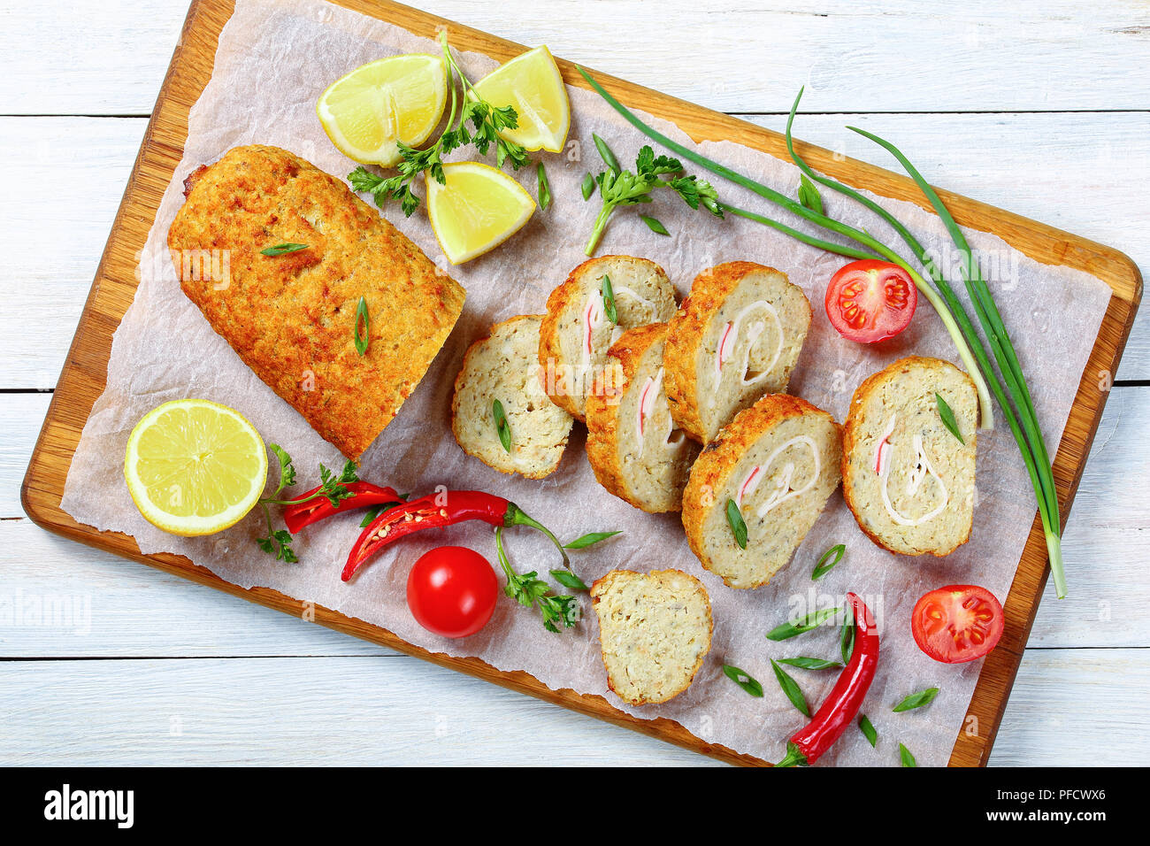 Nahaufnahme der hausgemachte Hackfleisch Fisch Brot mit Zwiebel, Eier, Karotten, in Scheiben geschnitten und serviert mit grünen Frühling Frühlingszwiebeln, Petersilie, Tomate, Scheiben Stockfoto
