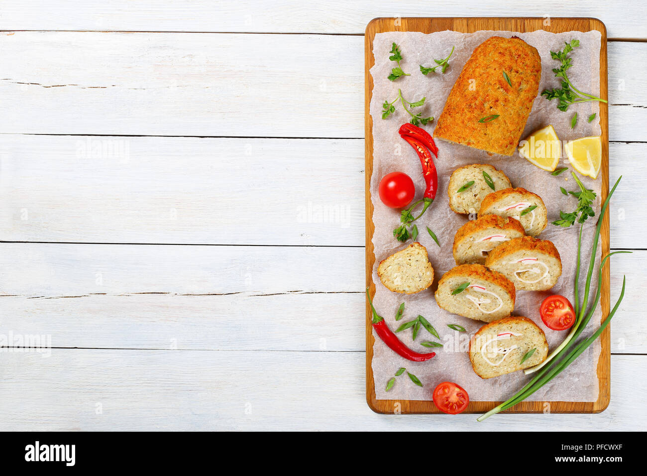 Lecker gebacken in Backofen Gefilte Hackfleisch/weißer Fischfilets Roll-up mit Krabbenfleisch in Scheiben geschnitten auf Schneidebrett mit Frühlingszwiebeln, Petersilie, frische Feder Stockfoto