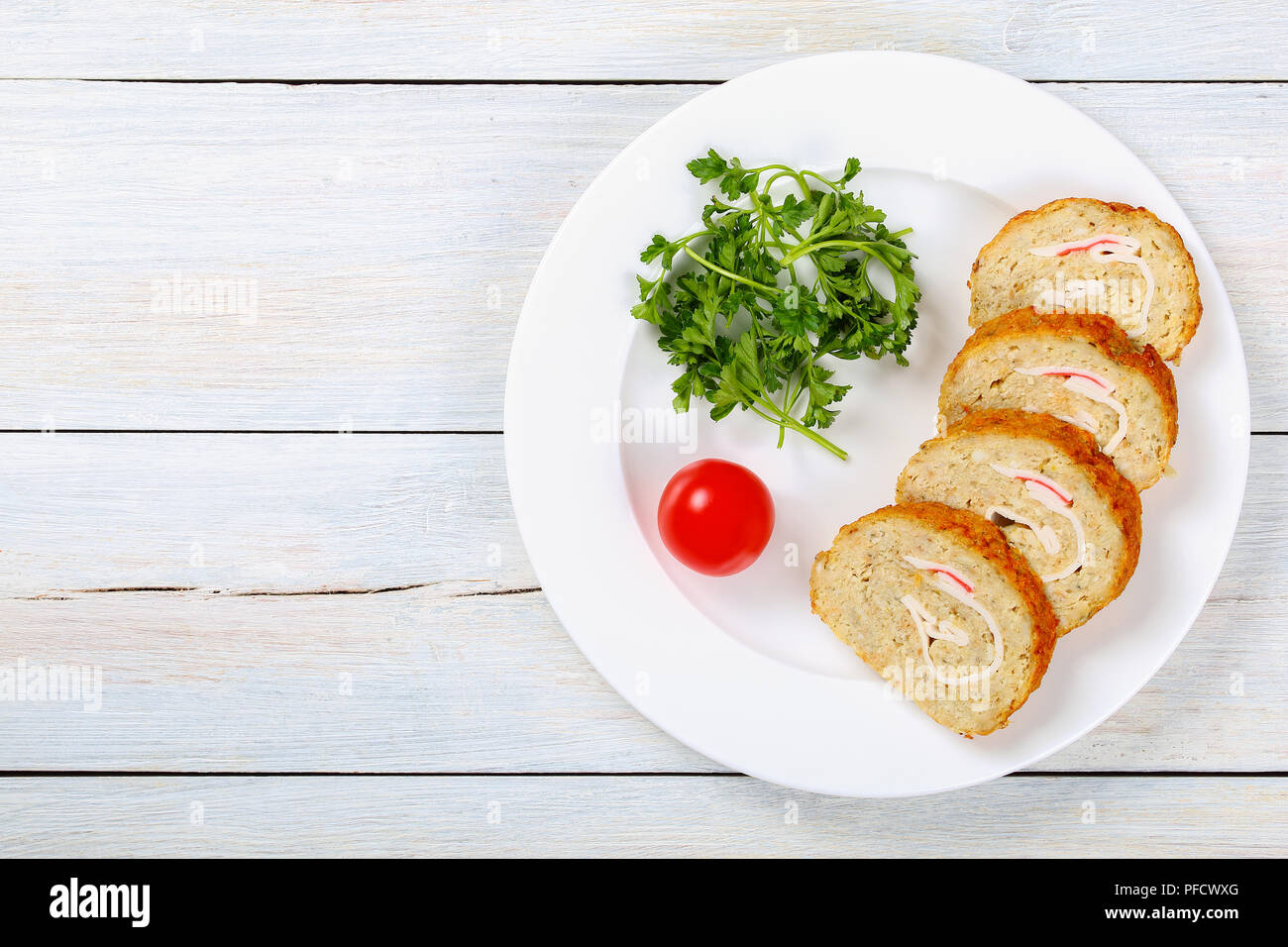 Leckeren, gesunden Backwaren in den Ofen Gefilte Hackfleisch/weißer Fischfilets Roll-up mit Krabbenfleisch in Scheiben geschnitten auf weiße Platte mit Petersilie und Tomaten, Anzeigen Stockfoto