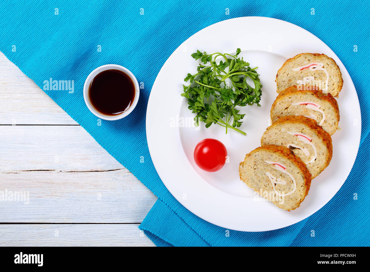 Leckeren, gesunden Backwaren in den Ofen Gefilte Hackfleisch/weißer Fischfilets Roll-up mit Krabbenfleisch in Scheiben geschnitten auf weissem Teller mit Petersilie und Tomaten, einfache rec Stockfoto