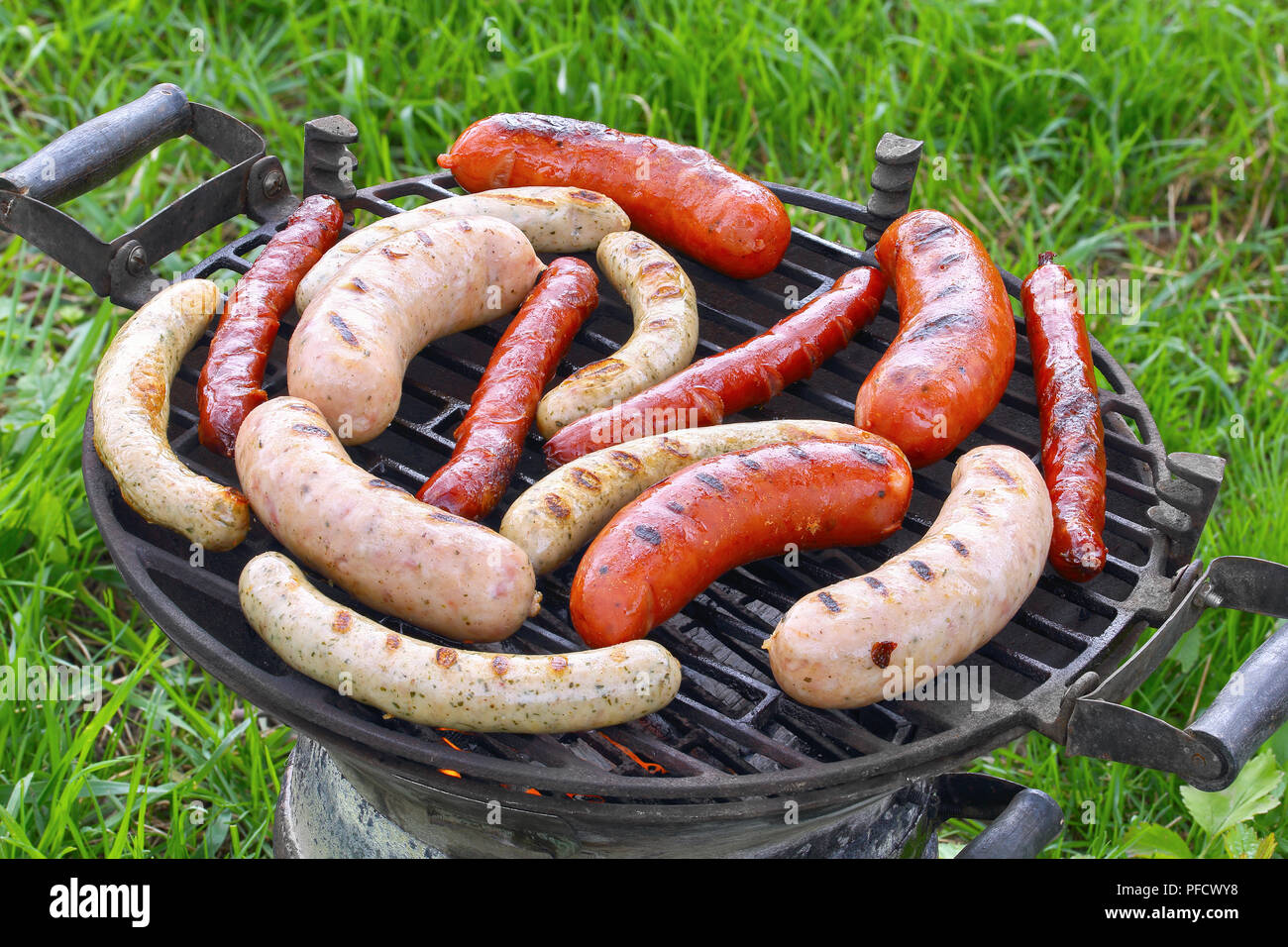 Gemischte Vielfalt leckerer char gegrillte Würstchen am Grill im Freien im Garten auf grünem Gras, Ansicht von oben Stockfoto