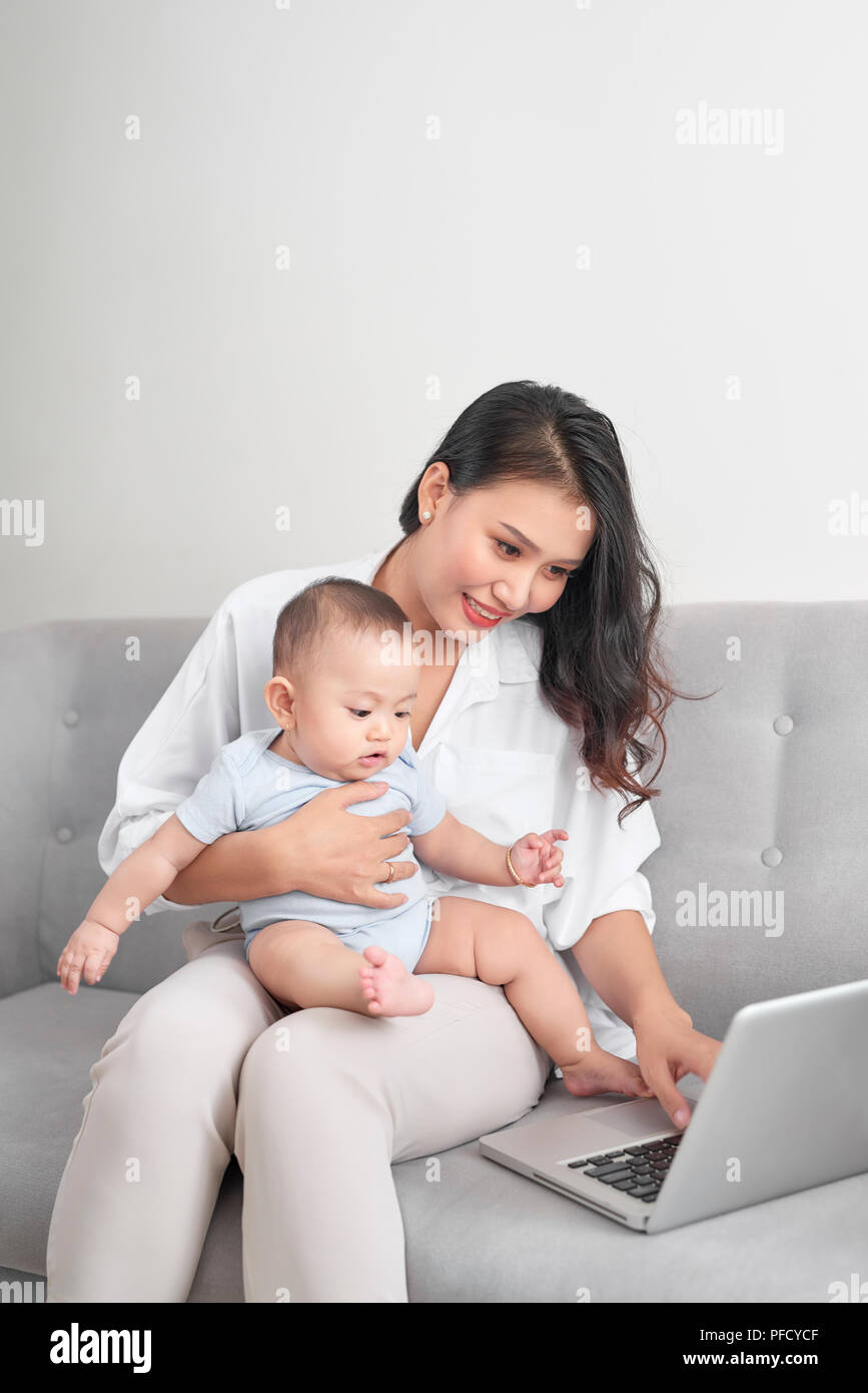 Junge Mutter mit Baby während der Arbeit im Home Office Stockfoto