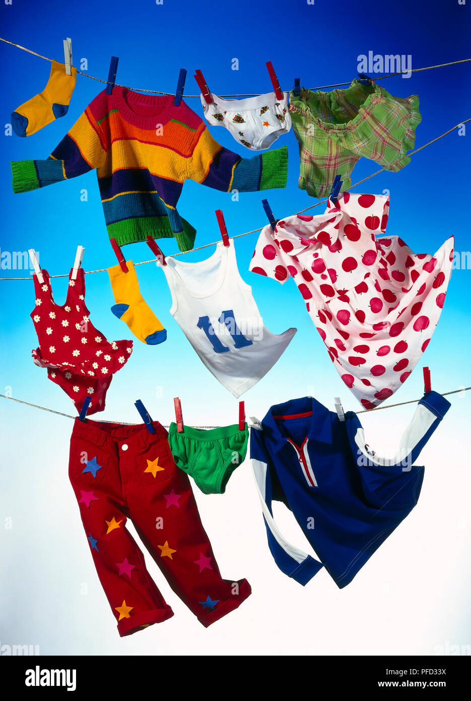 Elf Reihen von Kinderbekleidung hängen an drei Wäscheleine, blauer Hintergrund Stockfoto