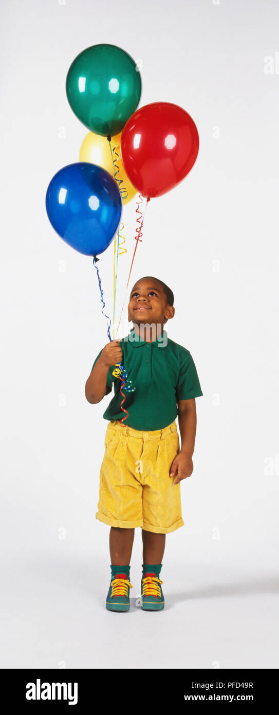 Junge Holding vier Gas gefüllte Ballone, Stockfoto