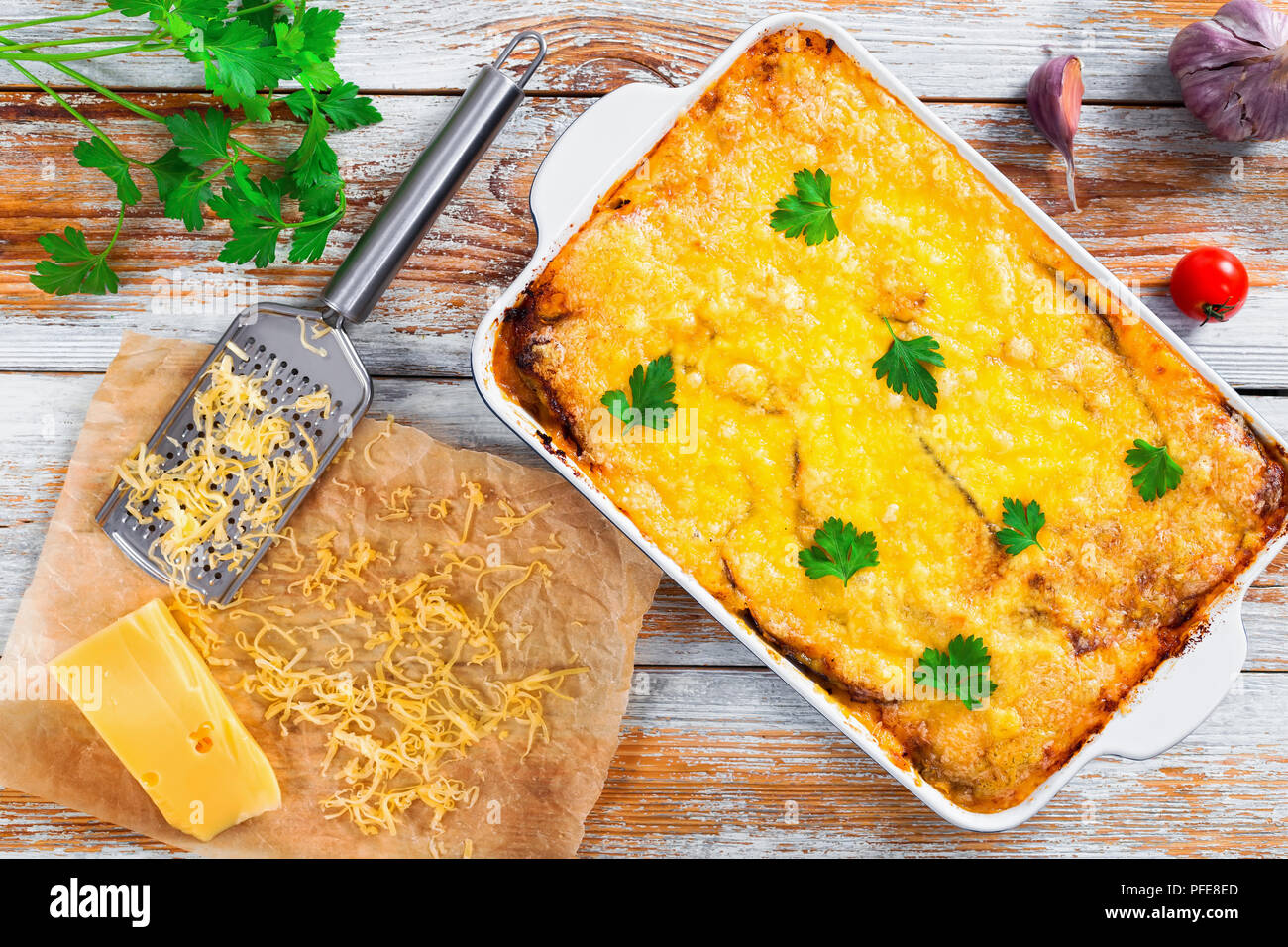 Moussaka, authentische Rezept - Schichten der Aubergine, Hackfleisch, Tomate, béchamelsoße Sauce und Käse in Schale. Reibe und ein Stück Käse, Petersilie, Knoblauch Stockfoto