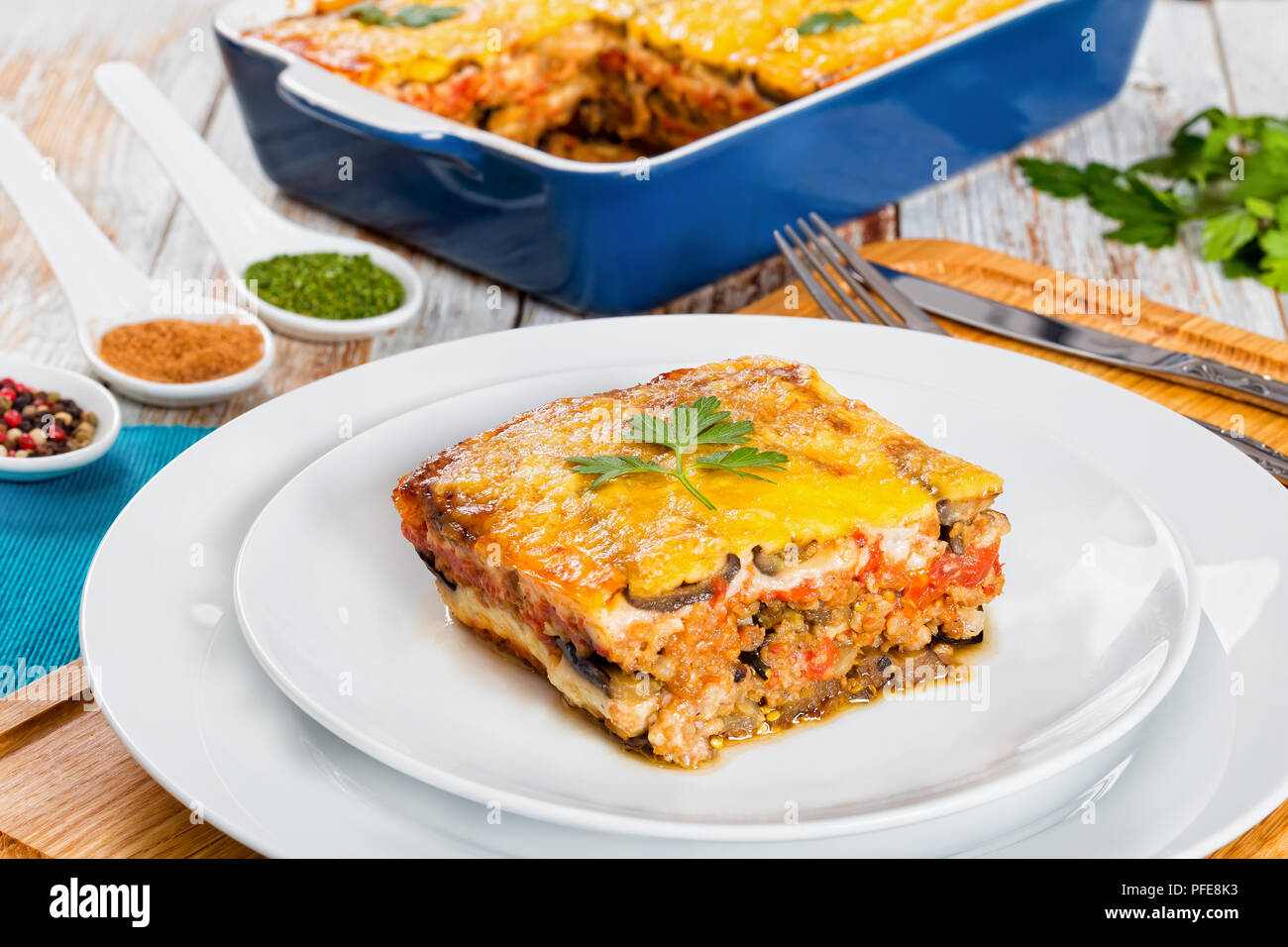 Teil der leckeren Moussaka mit Petersilie für authentische Rezept gekocht eingerichtet, auf Platten und in Gratin auf weißem abblätternde Farbe Boards, Ansicht von ab Stockfoto