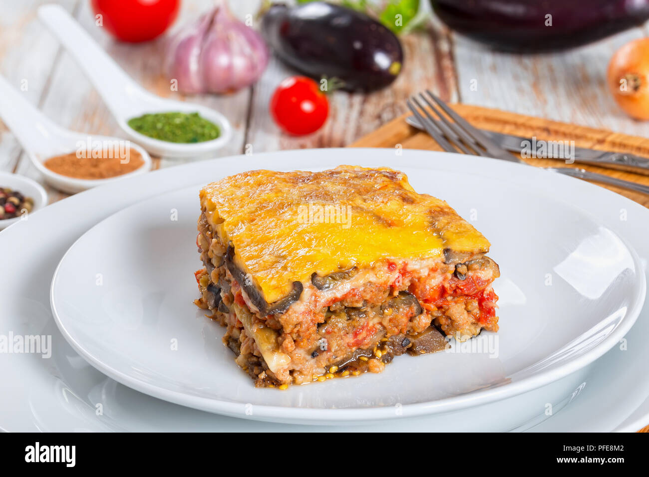 Teil der leckeren Moussaka mit Petersilie für authentische Rezept gekocht eingerichtet, auf Platten, auf weissem abblätternde Farbe Boards Stockfoto