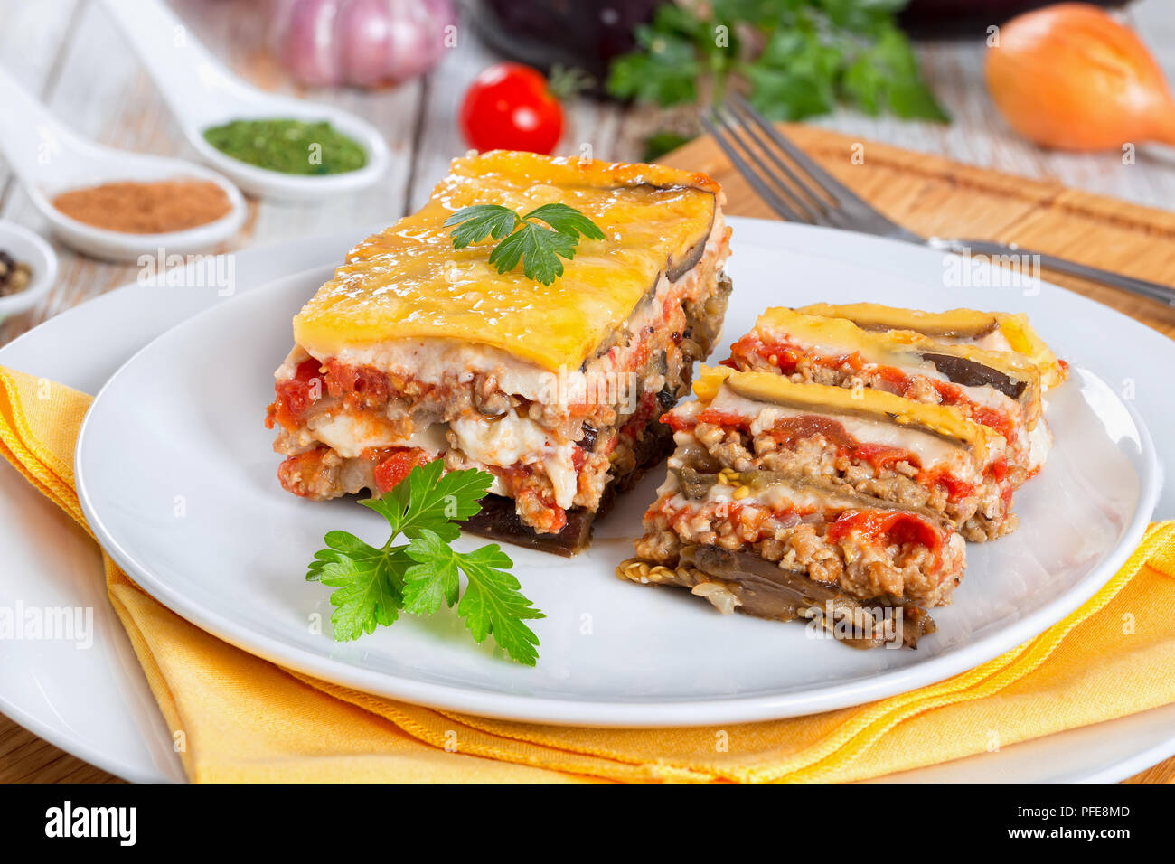 Teil der leckeren Moussaka mit Petersilie für authentische Rezept gekocht eingerichtet, auf Platten, auf weissem abblätternde Farbe Boards Stockfoto