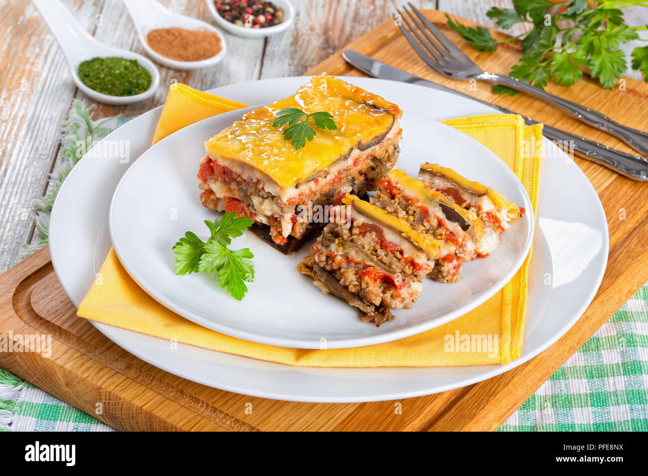 Teil der leckeren Moussaka mit Petersilie für authentische Rezept gekocht eingerichtet, auf Platten, auf weissem abblätternde Farbe Boards, Ansicht von oben Stockfoto