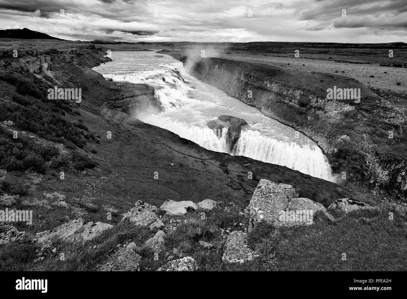 GULLFOSS, Island. 3. AUGUST 2016: Monochrom hohen Betrachtungswinkel von Gullfoss mit bewölktem Himmel im Hintergrund. Stockfoto