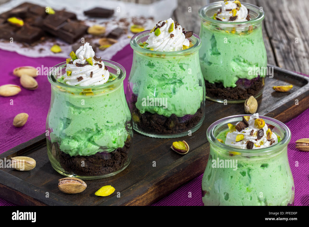 Keine Backen pistazie Käsekuchen ein Glas Kleinigkeit - einfache Hausgemachte layered Dessert für festliche Party oder Familie Abendessen auf dunklen Holzplatte, close-up Stockfoto