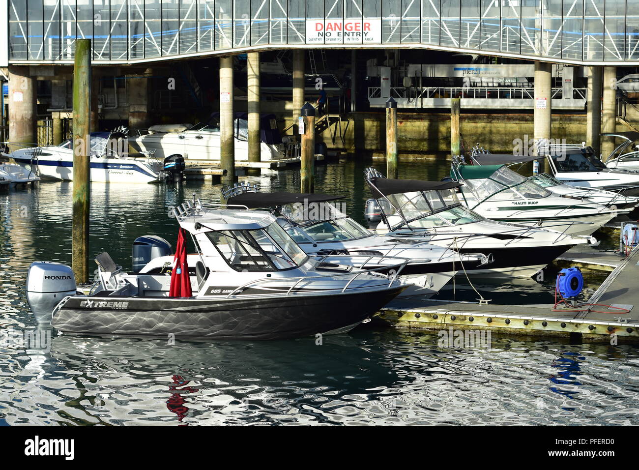 Power Boote mit Außenbordmotoren an schwimmenden Steg in der Marina. Licht Reflexion von Wasser Oberfläche erstellen Muster auf bootsrumpf. Stockfoto