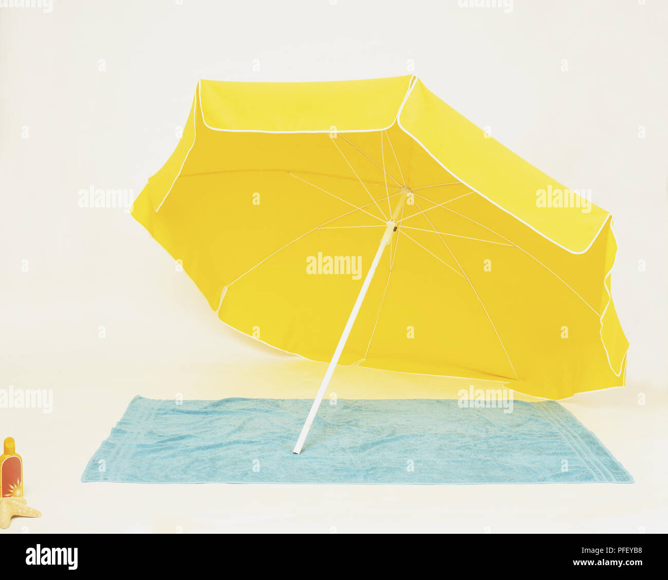 Gelber Strand Sonnenschirm schräg über Handtuch ruhen Stockfoto