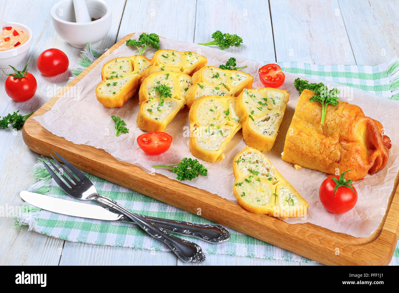 Crepes Brötchen mit gehacktem Hühnerfleisch, Cottage und Kräuter in Scheiben schneiden auf Schneidebrett mit frischer Petersilie und Tomaten gefüllt, Nahaufnahme, Ansicht Stockfoto