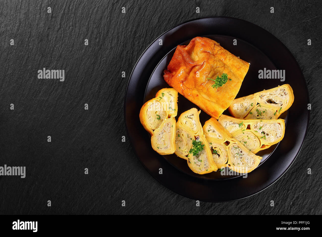 Crepes Brötchen mit gehacktem Hühnerfleisch, Cottage und Kräuter in Scheiben schneiden auf schwarze Platte auf schiefer Fach gefüllt, Ansicht von oben Stockfoto