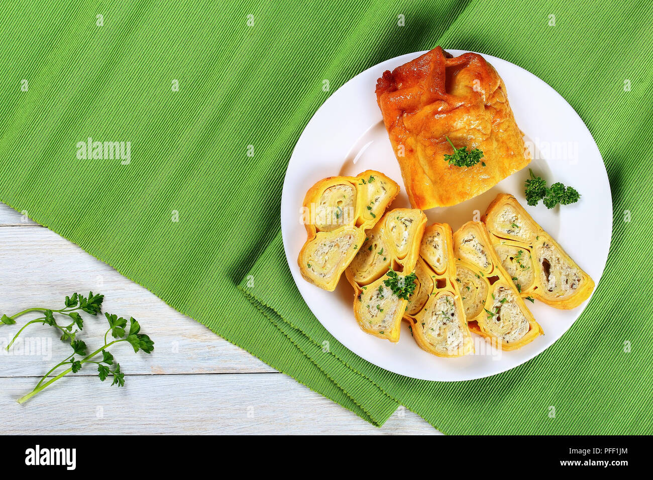 Köstliche Kuchen im Ofen gebackenen crepes Brötchen gefüllt mit gehacktem Hühnerfleisch, Cottage und Kräuter in Scheiben schneiden, mit Petersilie auf weiße Platte sprengte, Stockfoto