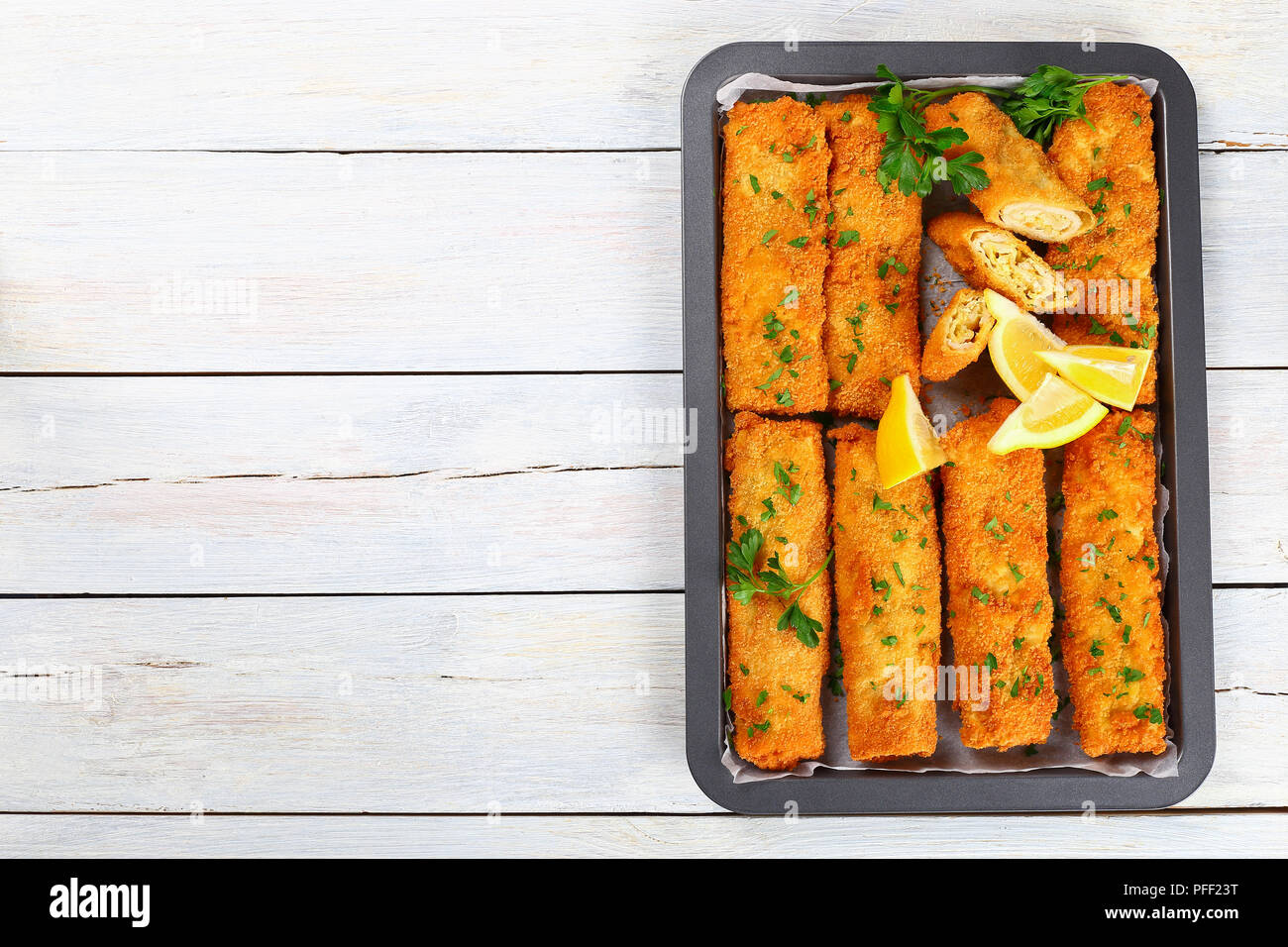 Lecker Knusprig paniert Gebackene Hackfleisch Huhn Chimichangas ganz und halbiert, mit gehackter Petersilie und Zitronenscheiben in Backen dis sprengte Stockfoto