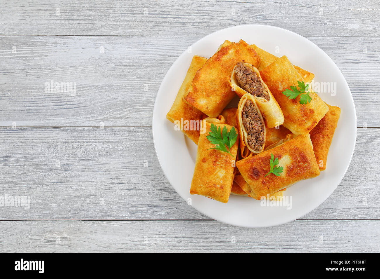 Lecker knusprig und heißen Pfannkuchen mit Hackfleisch gefüllt und Leber auf weiße Platte auf alten Holz- Tabelle, Ansicht von oben Stockfoto