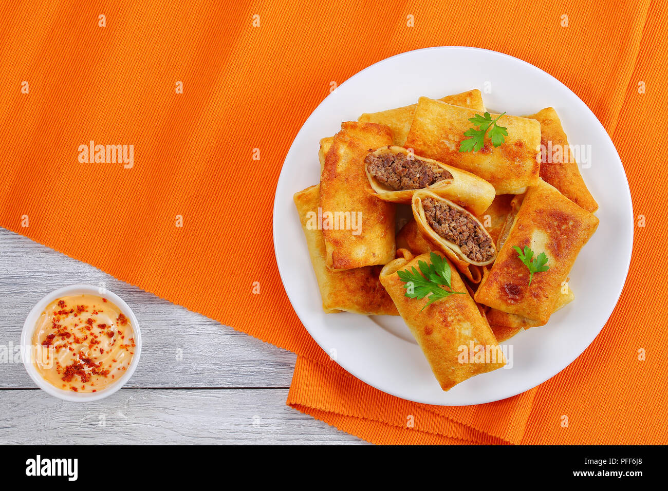 In Olivenöl lecker knusprig und warme Crepes gefüllt mit Hackfleisch/Leber gebraten und rollte auf weiße Platte auf alten Holztisch mit Paprika Mayonnaise s Stockfoto