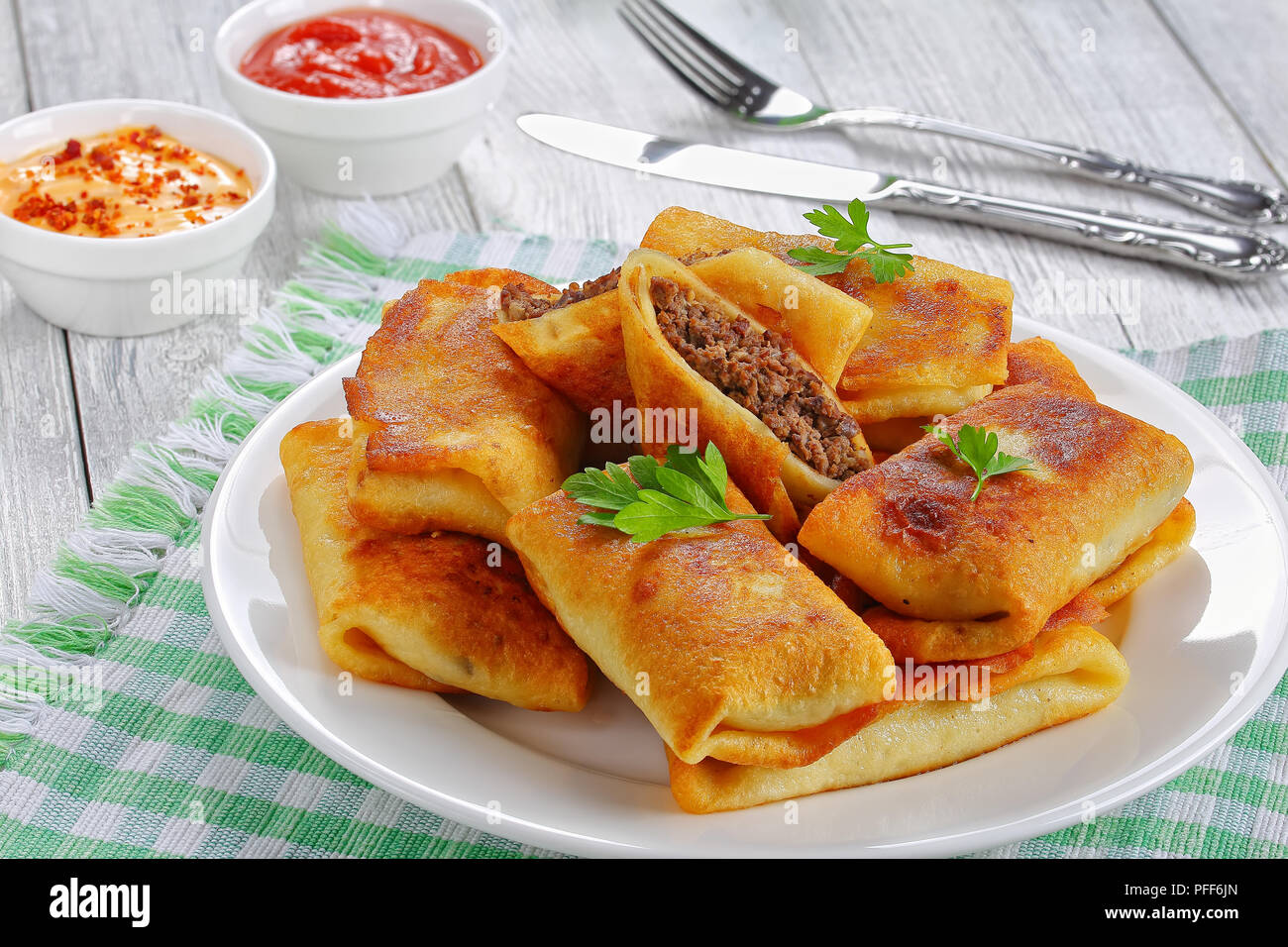 Aufgerollt köstliche Crêpes mit Hackfleisch/Leber und Fleisch auf weiße Platte auf alten Holztisch mit sauceon Hintergrund Blick von oben, in der Nähe gefüllt - Bis Stockfoto