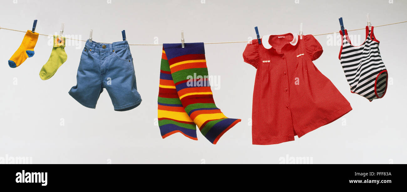 Socken, Shorts, Schal, Kleid und Badekleidung hängen von der Wäscheleine, Vorderansicht. Stockfoto
