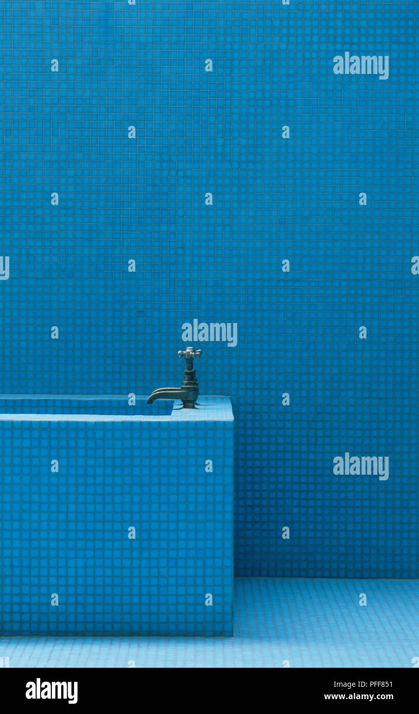 Badezimmer Wände, Boden und oberen Ende der rechteckige Badewanne mit Bronze farbigen Armaturen, mit identischen, winzigen blauen Fliesen bedeckt Stockfoto