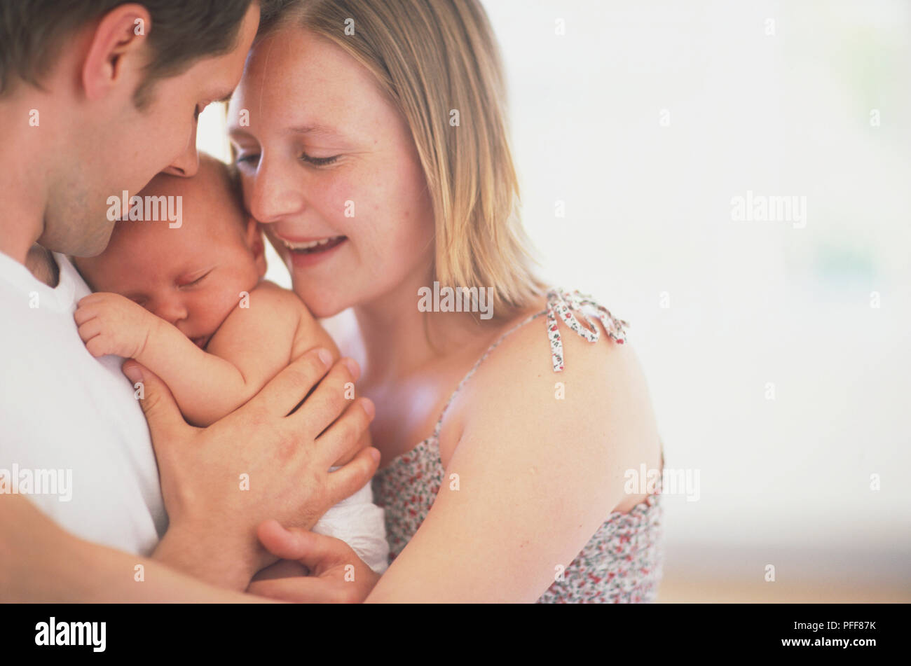 Lächelnd Mann und eine Frau umarmen schlafendes Baby, Seitenansicht. Stockfoto