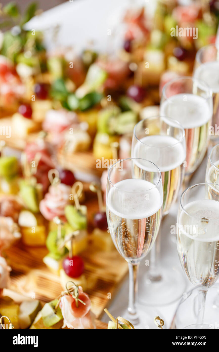 Feierlichen Rutsch ins neue Jahr und Veranstaltungsräume. Viele Gläser Champagner oder Wein auf dem Tisch im Restaurant Buffet mit vielen leckeren Snacks. Canapees, Bruschetta, und kleine Desserts auf Holzplatte board Stockfoto