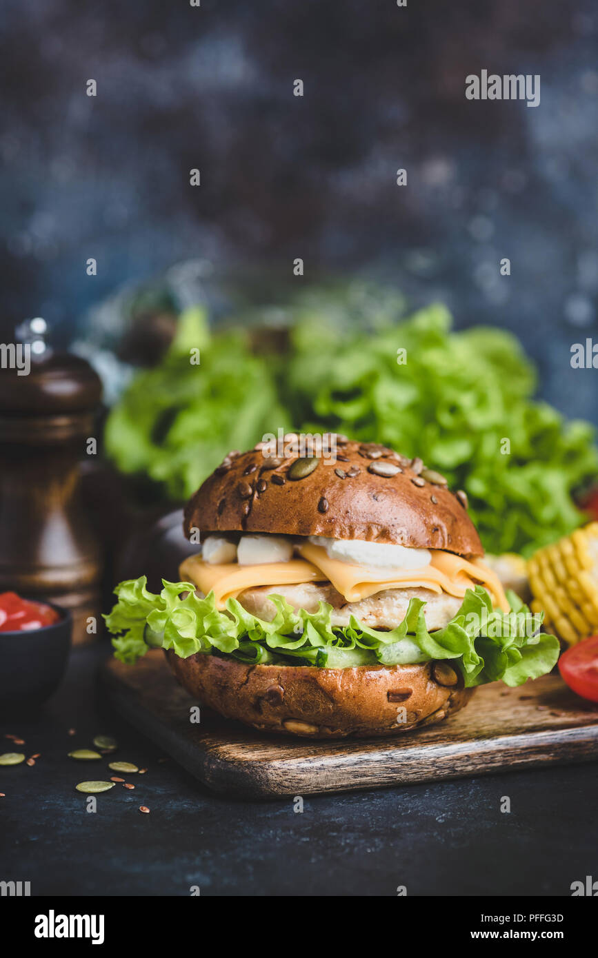 Leckere Chicken Burger mit Käse, Sauce, Salat auf Holz- dienen. Detailansicht, selektiver Fokus Stockfoto