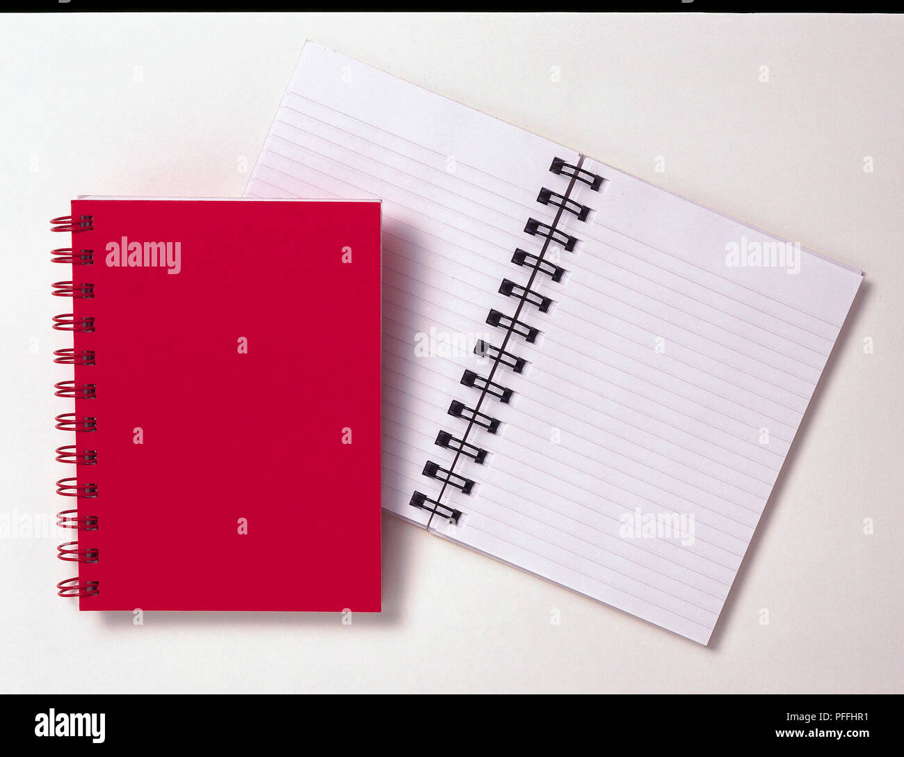 Notebook mit einer roten Jacke und eine offene Notebook mit ausgeschlossen/gesäumt leeres Papier. Stockfoto